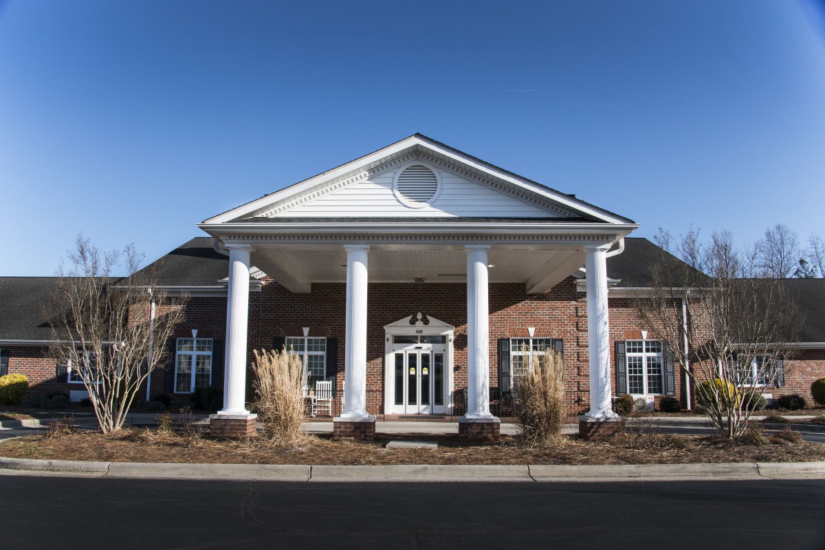 A symmetrical building with large white columns and a brick exterior.
