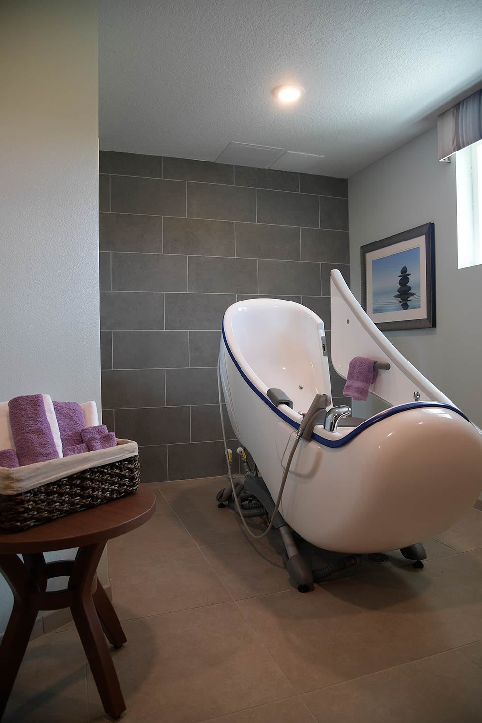 A modern bathroom featuring a unique spa bathtub with lavender towels and minimalist decor.
