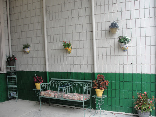 A cozy corner featuring a decorative bench and potted plants against a green and white tiled wall.