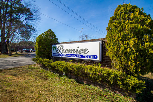 Premier Business Center sign surrounded by lush greenery under a clear blue sky.