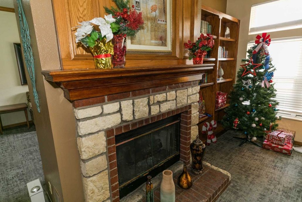A cozy living room corner featuring a decorated fireplace mantel and a Christmas tree.