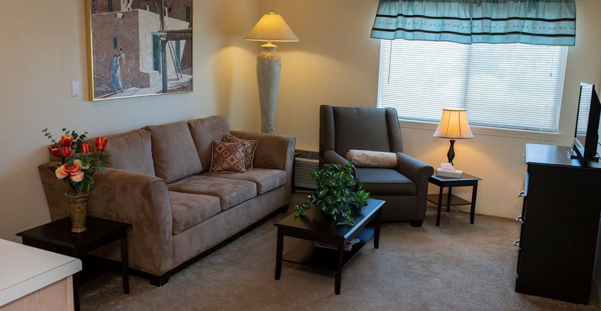 A cozy living room with a sofa, armchair, coffee table, and various lighting.
