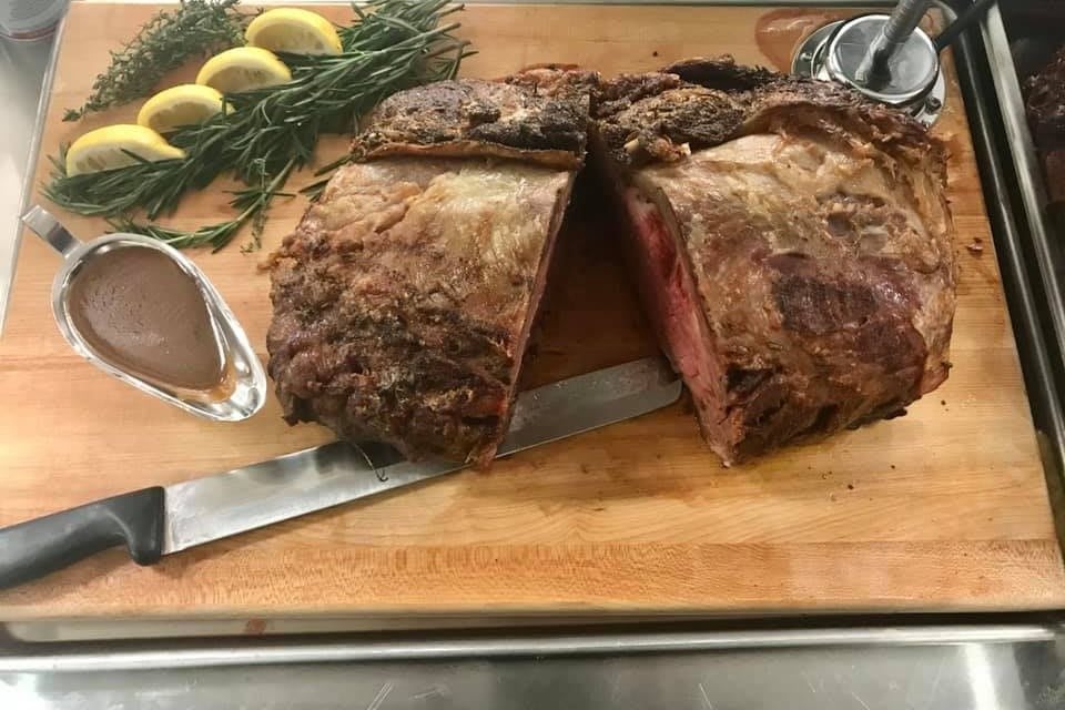 A succulent roast beef sliced on a wooden cutting board, garnished with lemons and rosemary.
