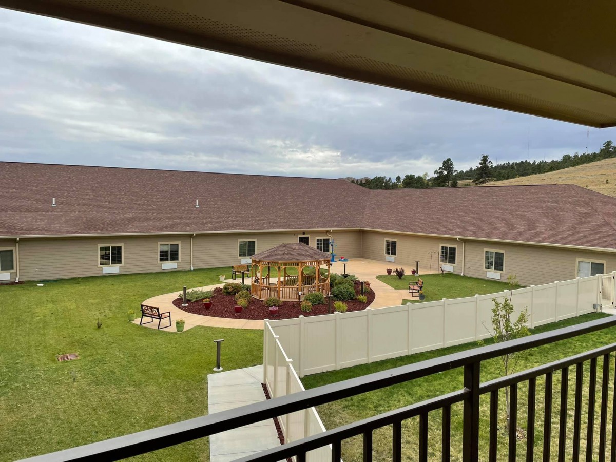 A view overlooking a courtyard garden with a surrounding building and overcast sky.