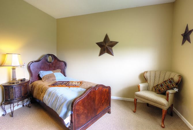 A simple bedroom with a wooden bed, a chair, and star wall decoration.