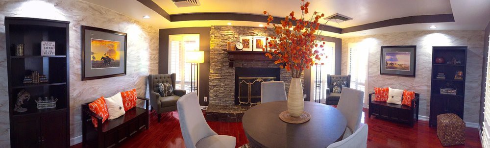 A cozy living room featuring a stone fireplace and modern decor accents, including a vase with vibrant flowers.