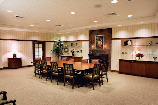 A well-appointed conference room featuring a large wooden table surrounded by chairs, complemented by decorative wall art and indoor plants.