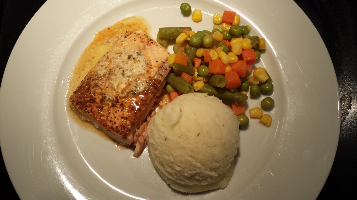 A dinner plate featuring salmon, mashed potatoes, and mixed vegetables.