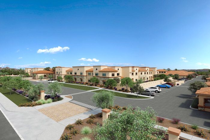 A view of a modern apartment complex with a parking lot on a sunny day.