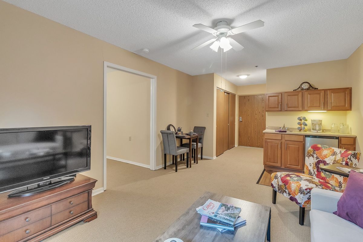 A cozy living space featuring a TV, dining table, and kitchen area with warm lighting.