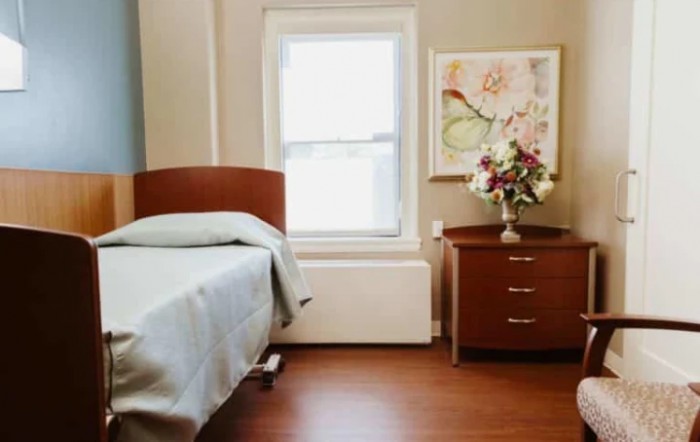 A simple bedroom with a single bed, nightstand, and floral decorations.