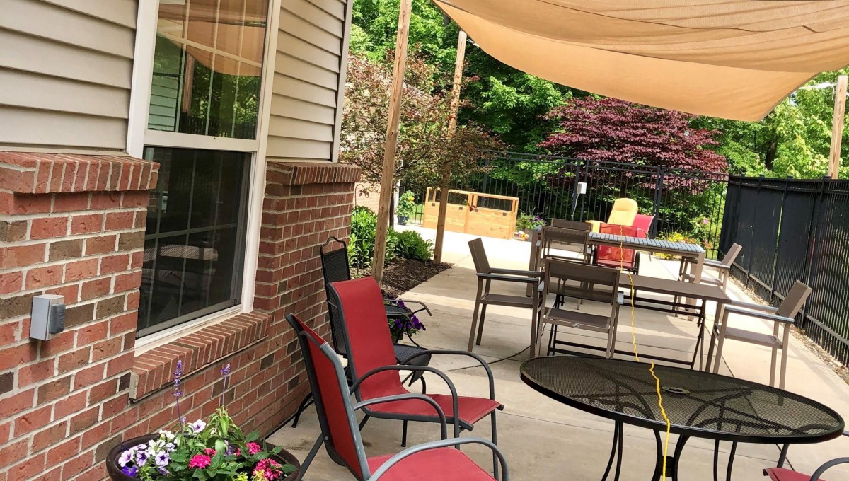 A cozy outdoor patio with seating, tables, and a shade sail.