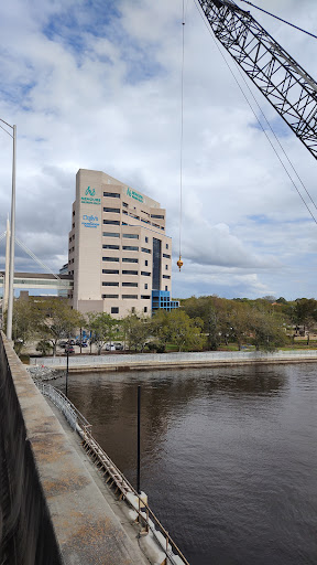 A view of a modern building situated by the river, under a cloudy sky.