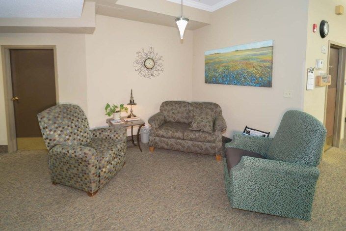 A cozy living room featuring patterned armchairs, a sofa, and wall decor.
