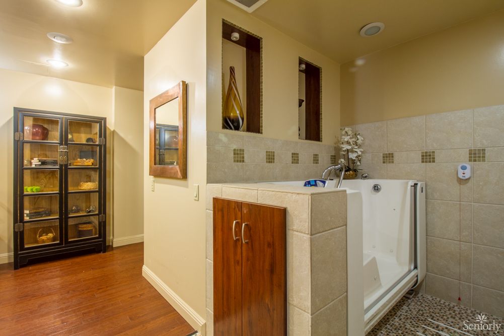 A modern bathroom with a walk-in tub and elegant wooden accents.