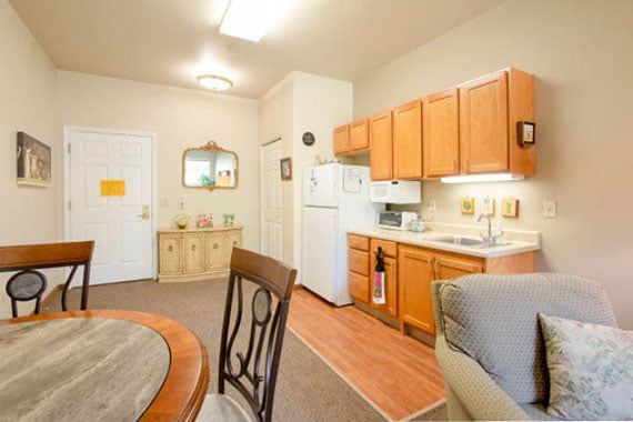 A cozy apartment kitchen with a small dining area and wooden cabinetry.