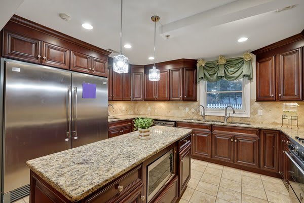 A modern kitchen featuring granite countertops, wood cabinetry, and stainless steel appliances.