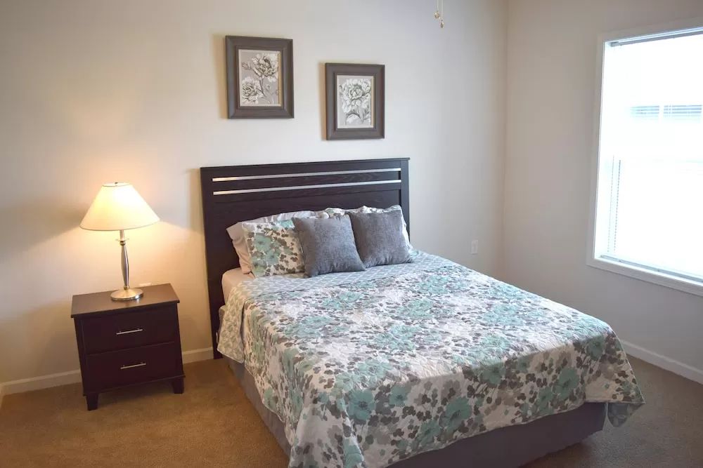 A cozy bedroom with a neatly made bed, nightstand, and decorative wall art.