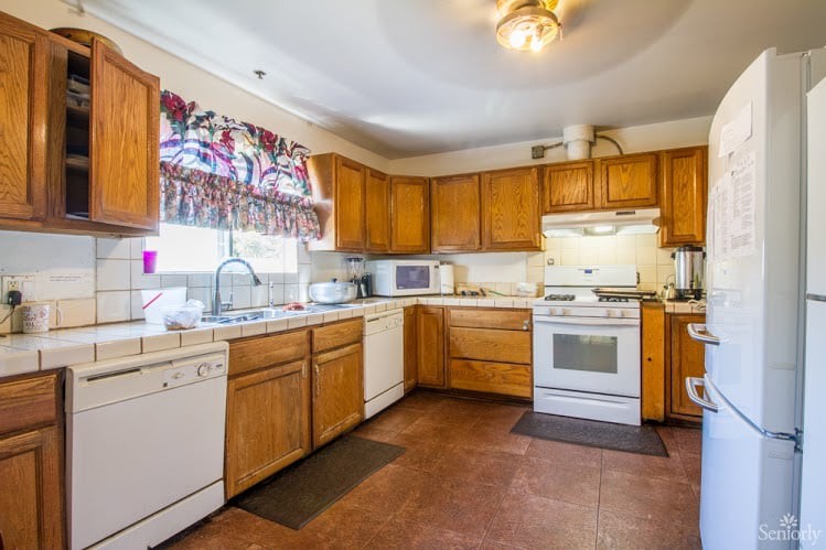 A spacious kitchen with wooden cabinets, featuring modern appliances such as an oven and microwave.