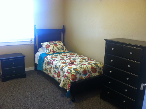 A cozy bedroom featuring a single bed with floral bedding and a matching dresser.
