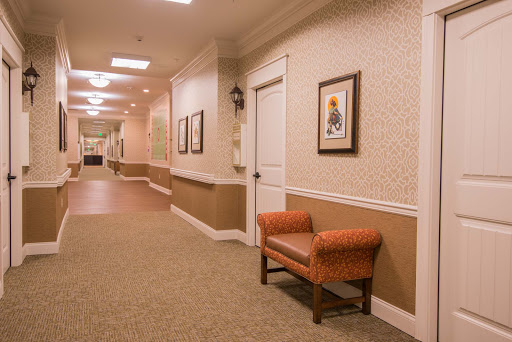 A well-lit hallway featuring an orange chair and framed artwork on the walls.