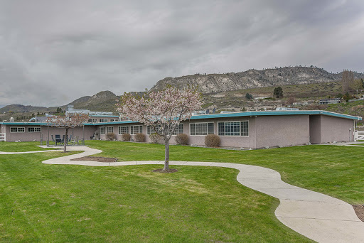 A view of a school building set against a mountainous landscape under a cloudy sky.