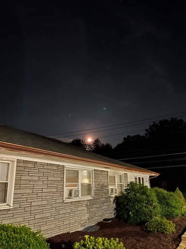 A serene night view featuring the moon rising behind a building.