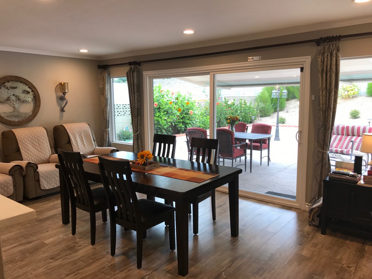 A modern dining area with a table and chairs, featuring a sliding door leading to an outdoor patio.