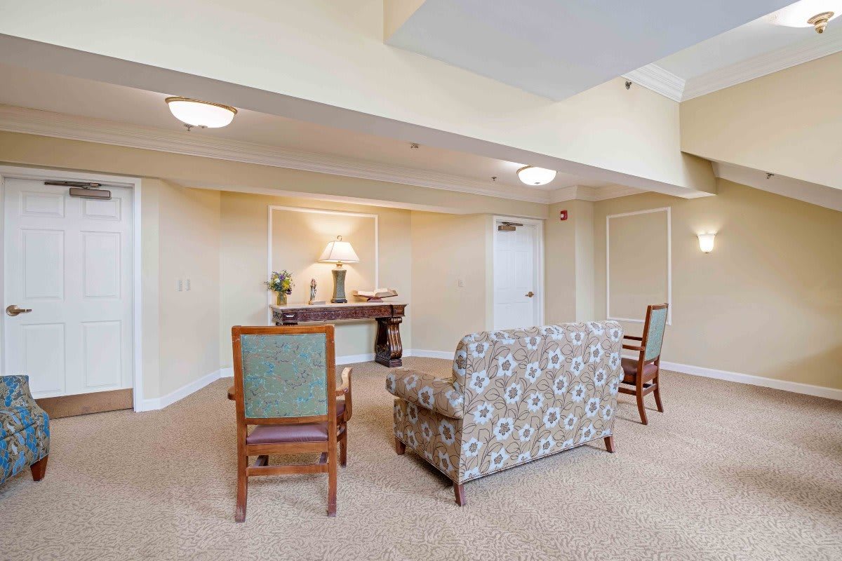 A cozy seating area with sofas and chairs arranged around a table in a warmly lit room.