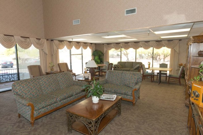 A spacious living room with sofas, a coffee table, and large windows with curtains.
