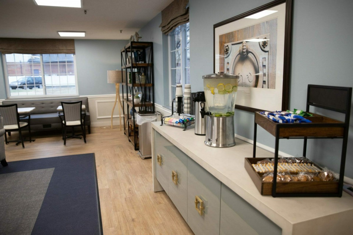 A cozy waiting room with a refreshment area featuring a water dispenser and comfortable seating.