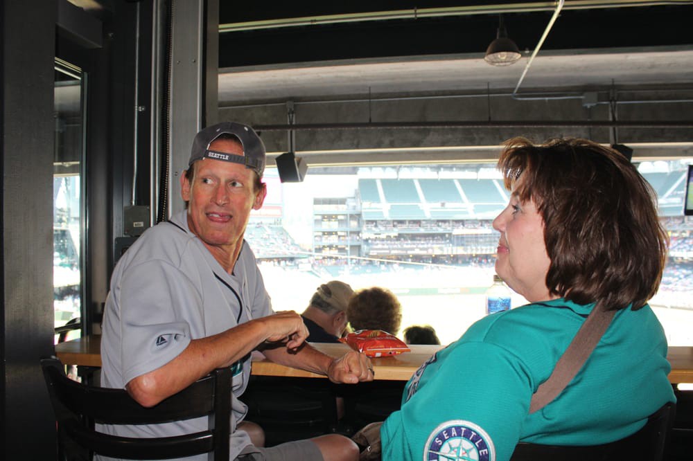 Two people enjoying a baseball game from a stadium seating area.