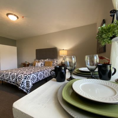 A cozy bedroom with a neatly arranged dining set in the foreground, combining comfort and style.