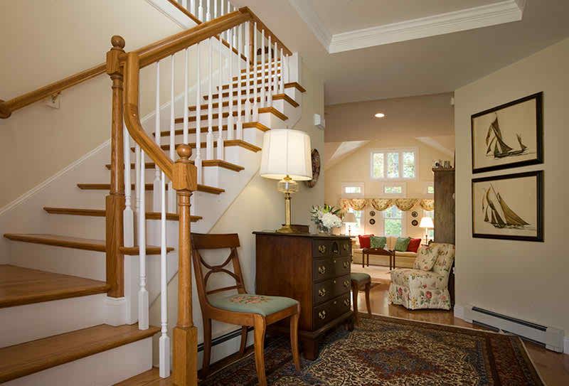 A cozy and traditionally decorated home with a wooden staircase leading into a warmly lit living room.