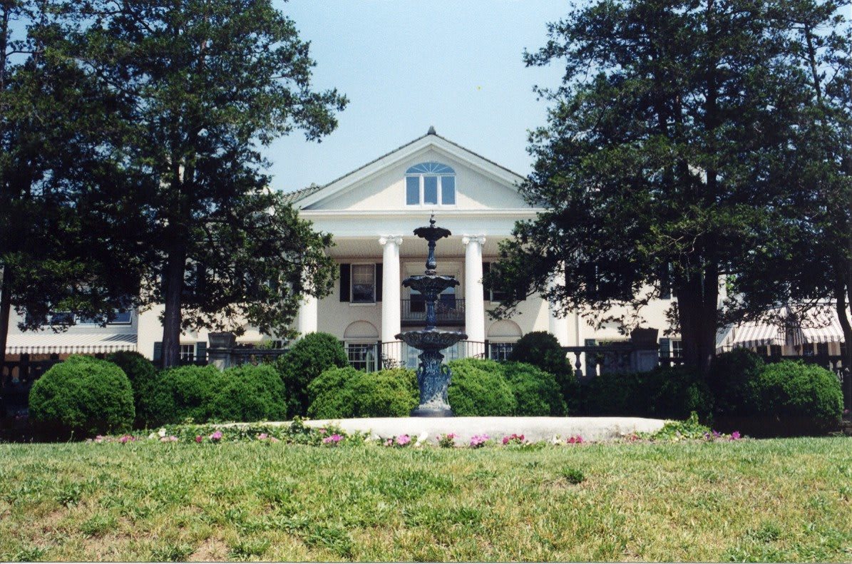 A grand mansion with tall columns and lush greenery.