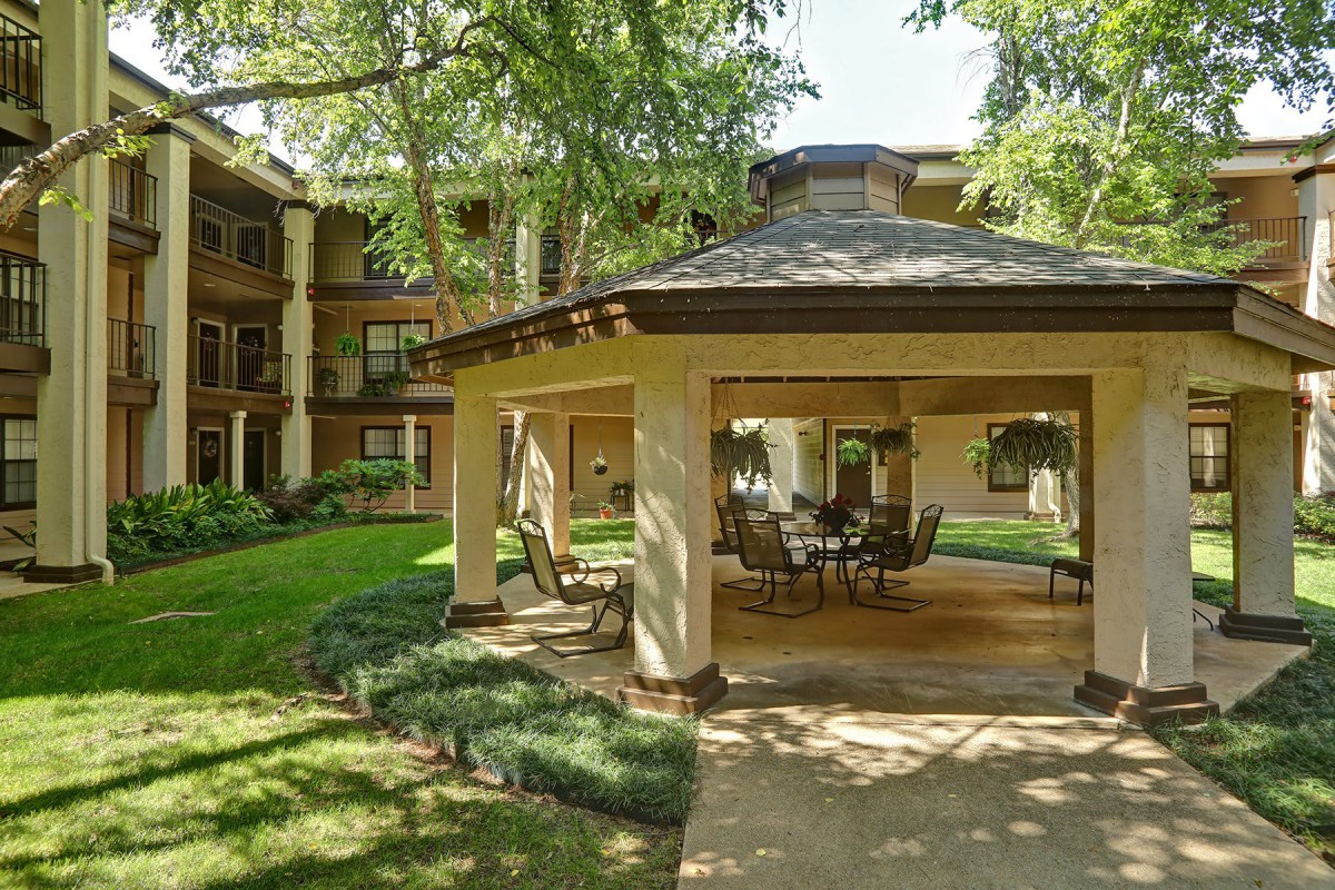 Outdoor gazebo area in a residential apartment complex surrounded by lush greenery.