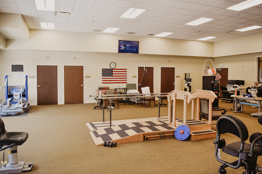 A spacious rehabilitation room featuring exercise equipment and an American flag on the wall.