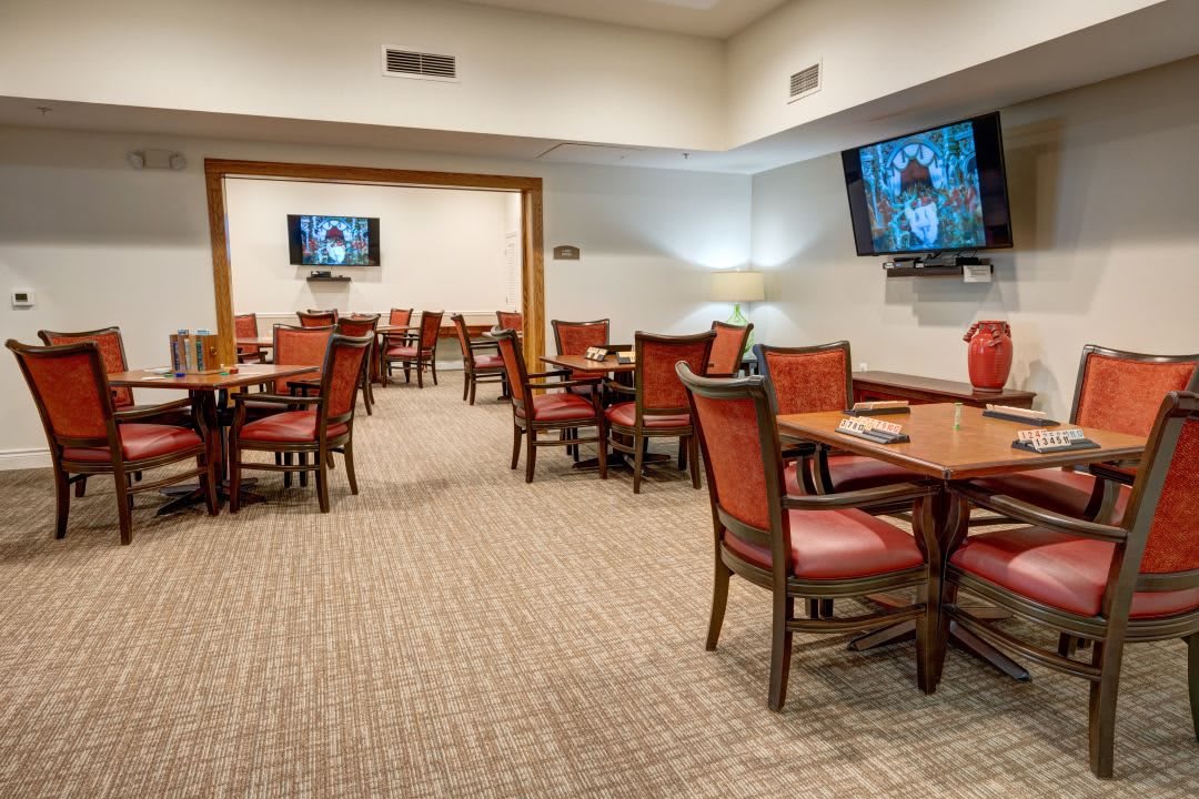 A spacious indoor dining area with tables, chairs, and multiple TV screens.