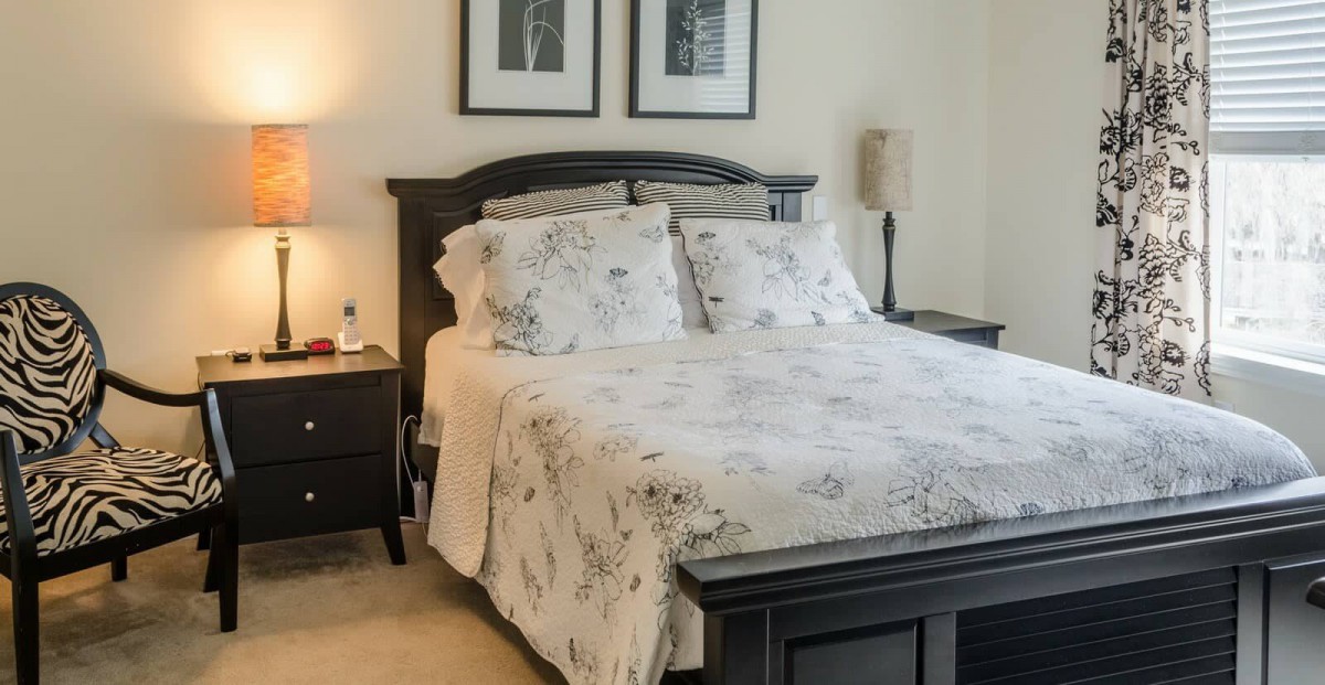 A cozy bedroom with a neatly made bed and elegant decor.
