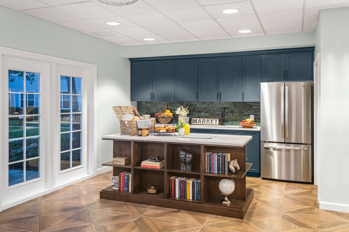 A modern kitchen with blue cabinets and a wooden island counter featuring built-in bookshelves.
