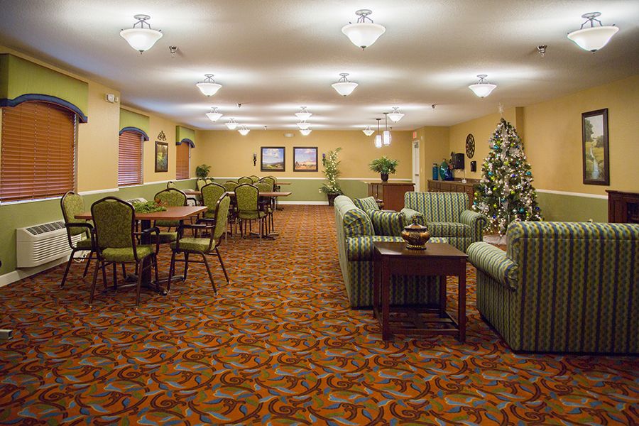 A well-furnished living area with sofas, tables, and chairs, lit by elegant light fixtures.