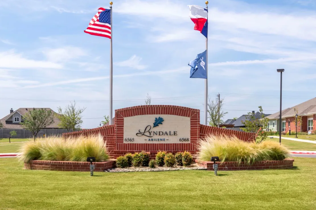 Entrance of The Villages neighborhood with flags and landscaping.