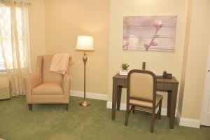 A cozy living space with a comfortable chair, floor lamp, and a sleek desk with artwork on the wall.