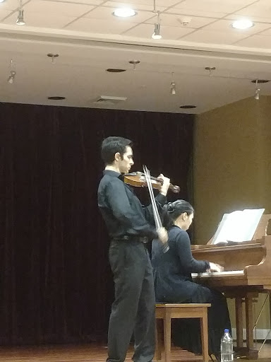 A violinist performing alongside a pianist during a musical duet.