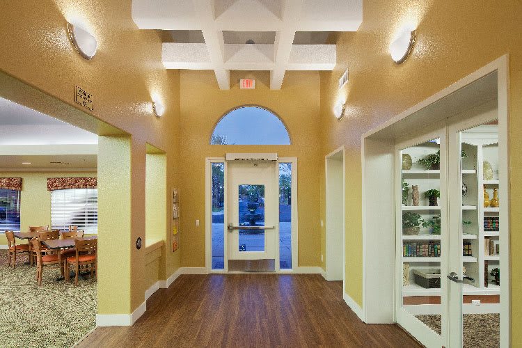 An interior view of a well-lit hallway with an entrance door and wooden flooring.