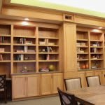 A well-organized library with wooden bookshelves and a table.