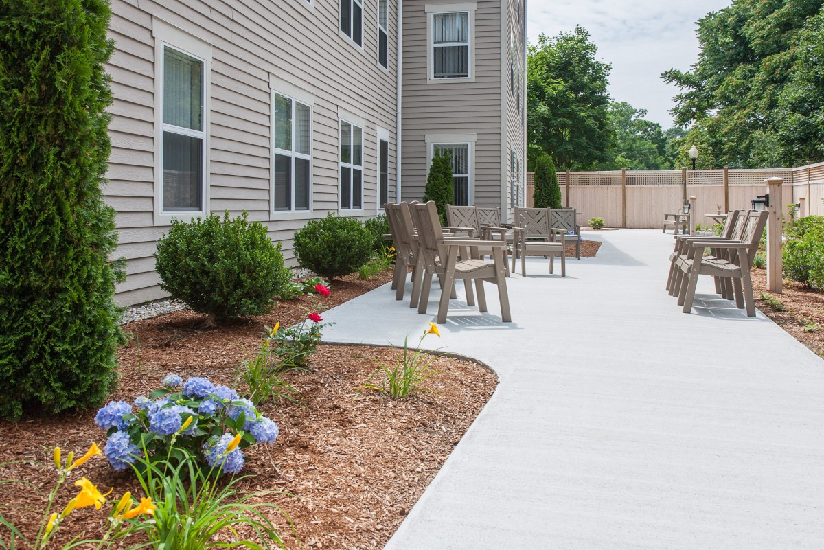A well-maintained patio area with chairs and landscaped garden outside a building.