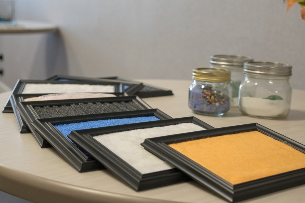 A collection of framed sand art pieces alongside jars filled with colorful sand.