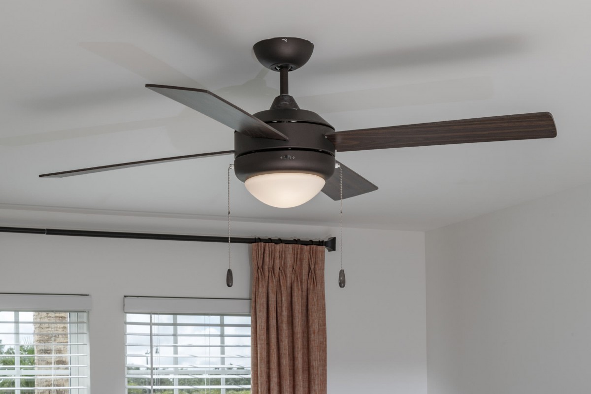 A modern ceiling fan with a built-in light fixture in a room setting.