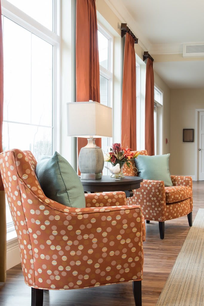 A cozy sitting area with patterned armchairs, a lamp, and decorative pillows.